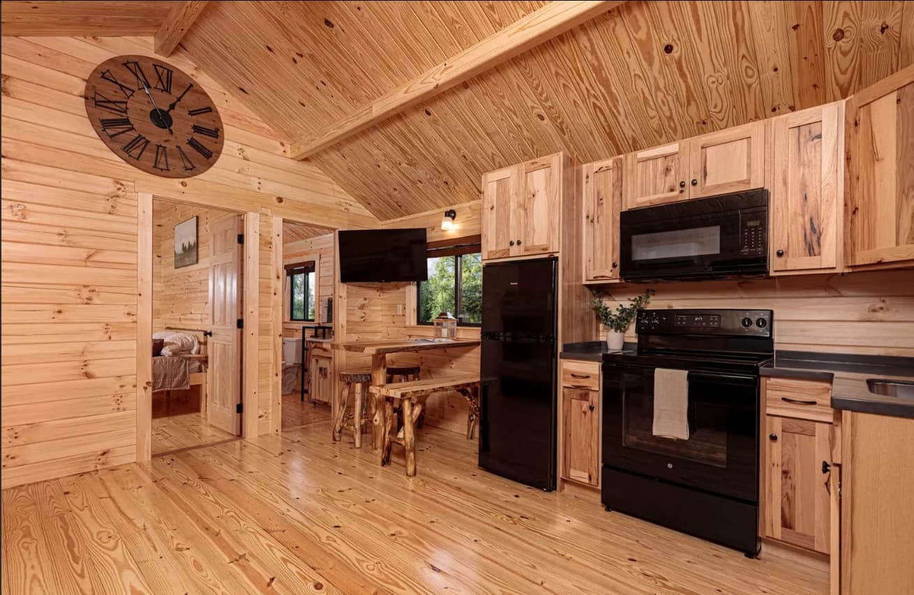Cabin kitchen and dining area with black appliances and wood interior