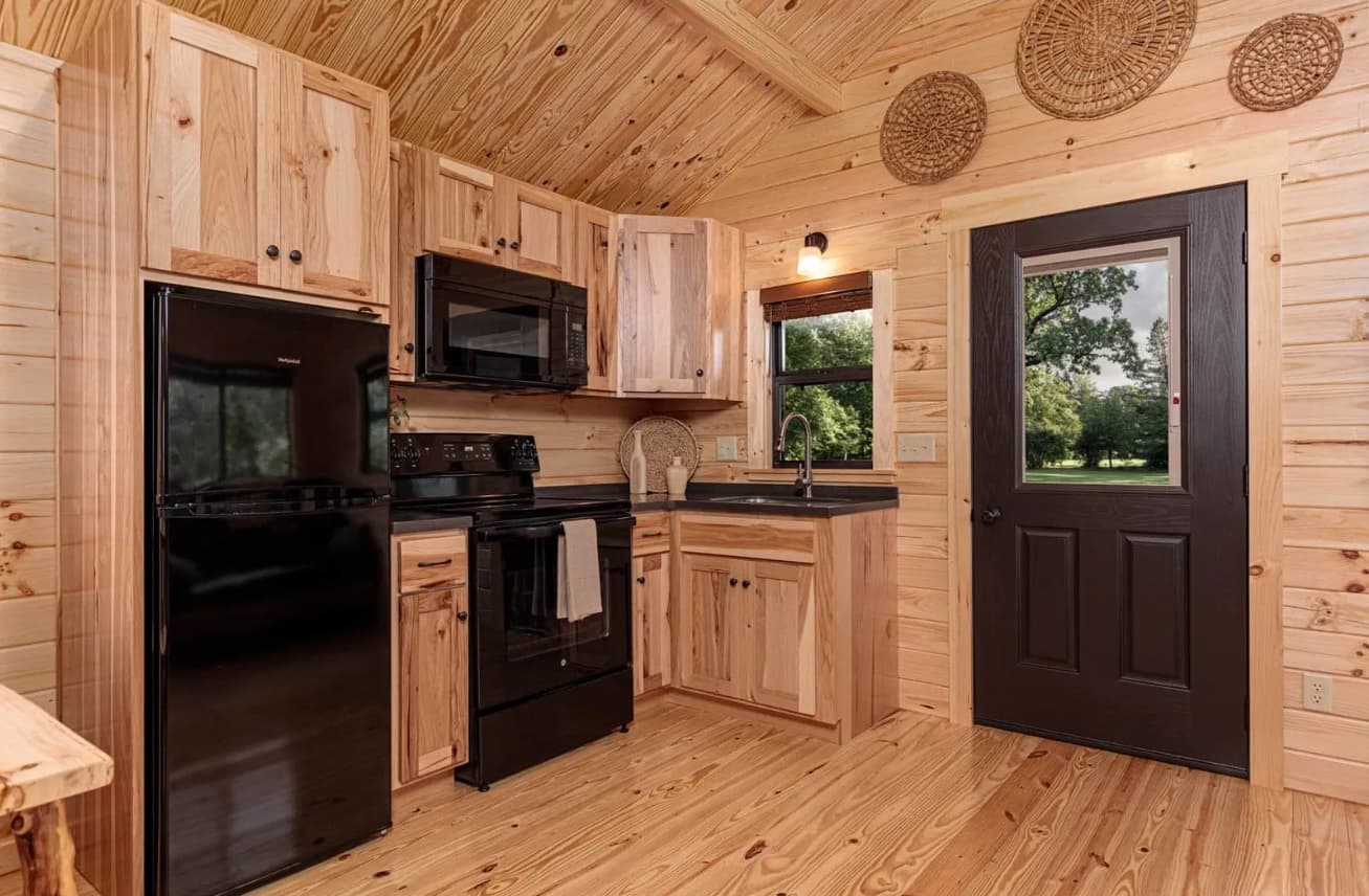 Compact cabin kitchen with black appliances and wood cabinetry