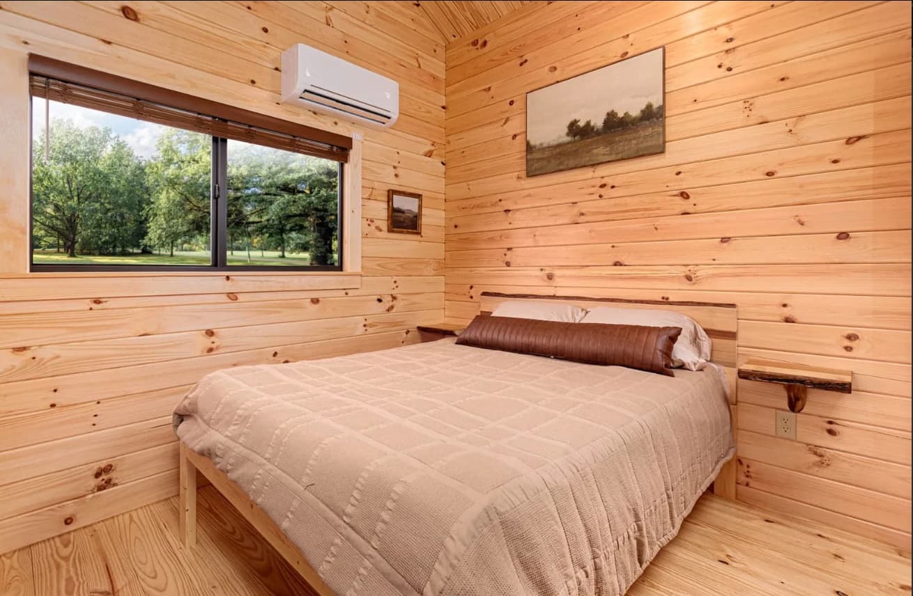 Cozy log cabin bedroom with large window and forest view