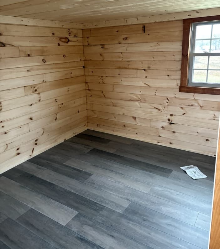 Small log cabin bedroom with pine wood paneling and natural light